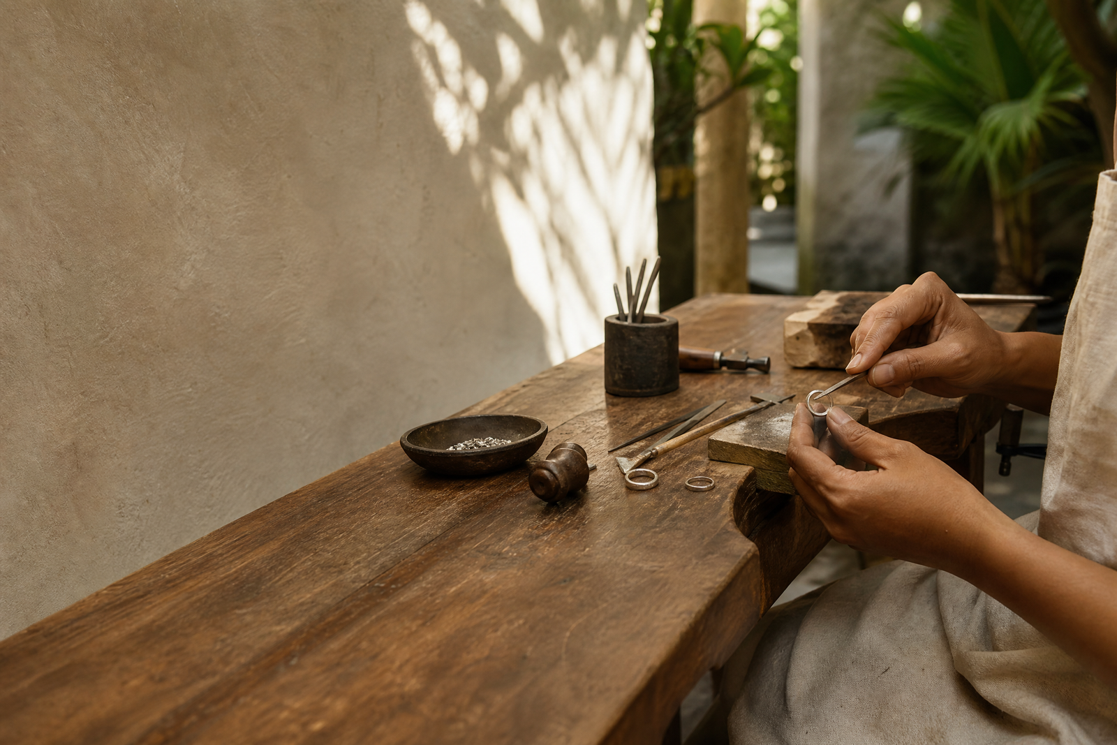 A silversmith working on a ring at a wooden workbench